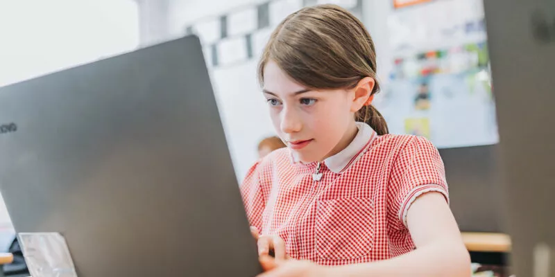 Pupil sat at a desk staring intently at a laptop