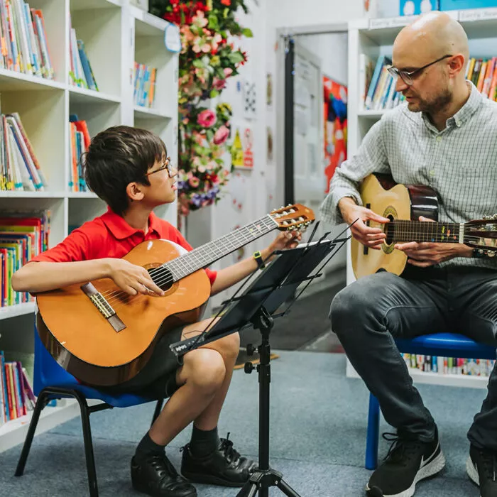 Child and teacher playing the guitar