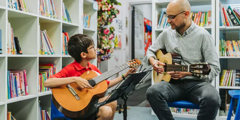 Child and teacher playing the guitar
